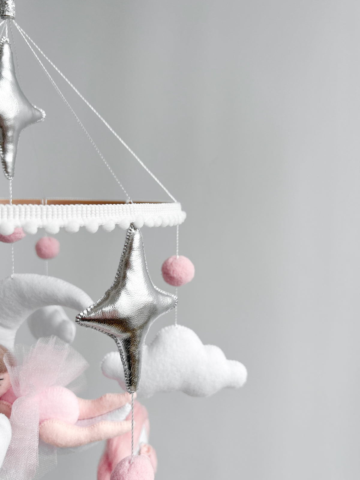 Dettaglio anello legno giostrina culla stelle argento pompon rosa nuvole bianche 