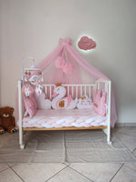 Lettino neonata rosa con baldacchino, paracolpi a treccia, giostrina mobile e cuscini decorativi a forma di cigno e nuvola.