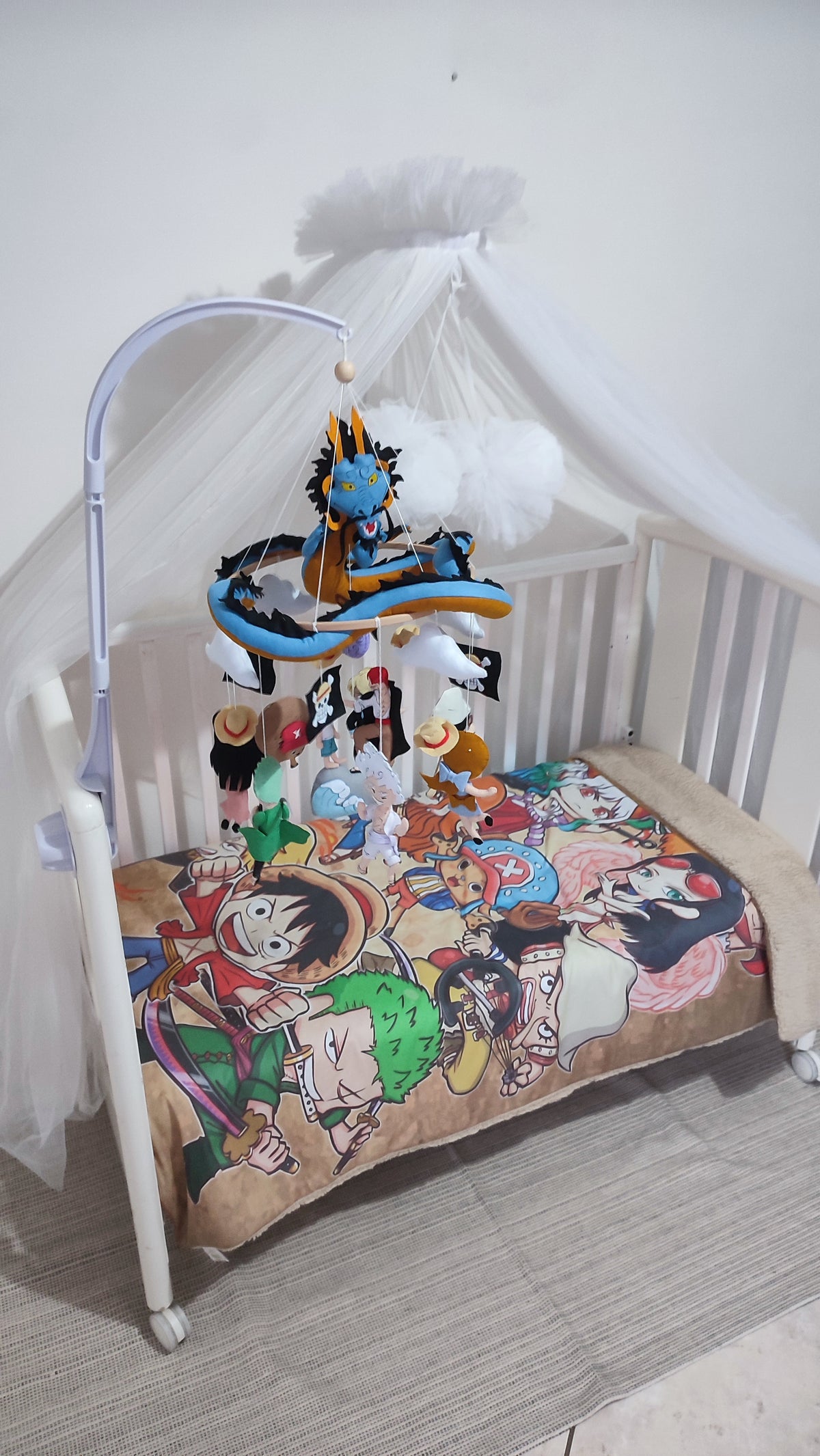 Mobile lettino legno One Piece montato con drago Kaido in feltro, nuvole e bandiere pirati, regalo nascita neonato anime.
