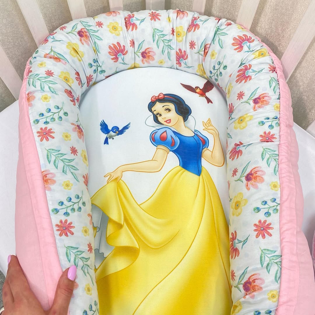 Baby nest rosa e bianco con stampa di Biancaneve, bordi imbottiti con fiorellini gialli e rossi per lettino culla.