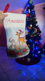 Calza di Natale azzurra dipinta a mano con illustrazione di Bambi e il coniglietto Tamburino tra rami di pino e bastoncini di zucchero.