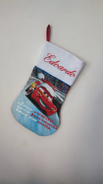 Calza di Natale azzurra dipinta a mano con illustrazione di Saetta McQueen con cappello natalizio e la scritta sono velocità.
