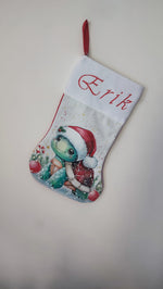Calza di Natale bianca dipinta a mano con illustrazione di una tartaruga con cappello di Babbo Natale e bastoncini di zucchero.