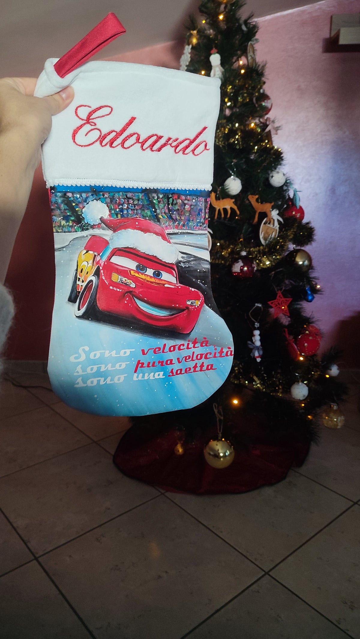 Calza di Natale azzurra dipinta a mano con illustrazione di Saetta McQueen con cappello natalizio e la scritta sono velocità.