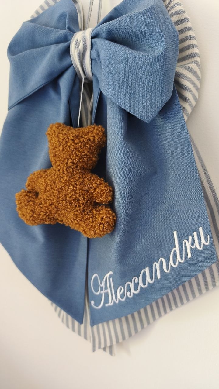 Dettaglio fiocco nascita azzurro jeans con orsetto bouclè color miele e nome ricamato in bianco
