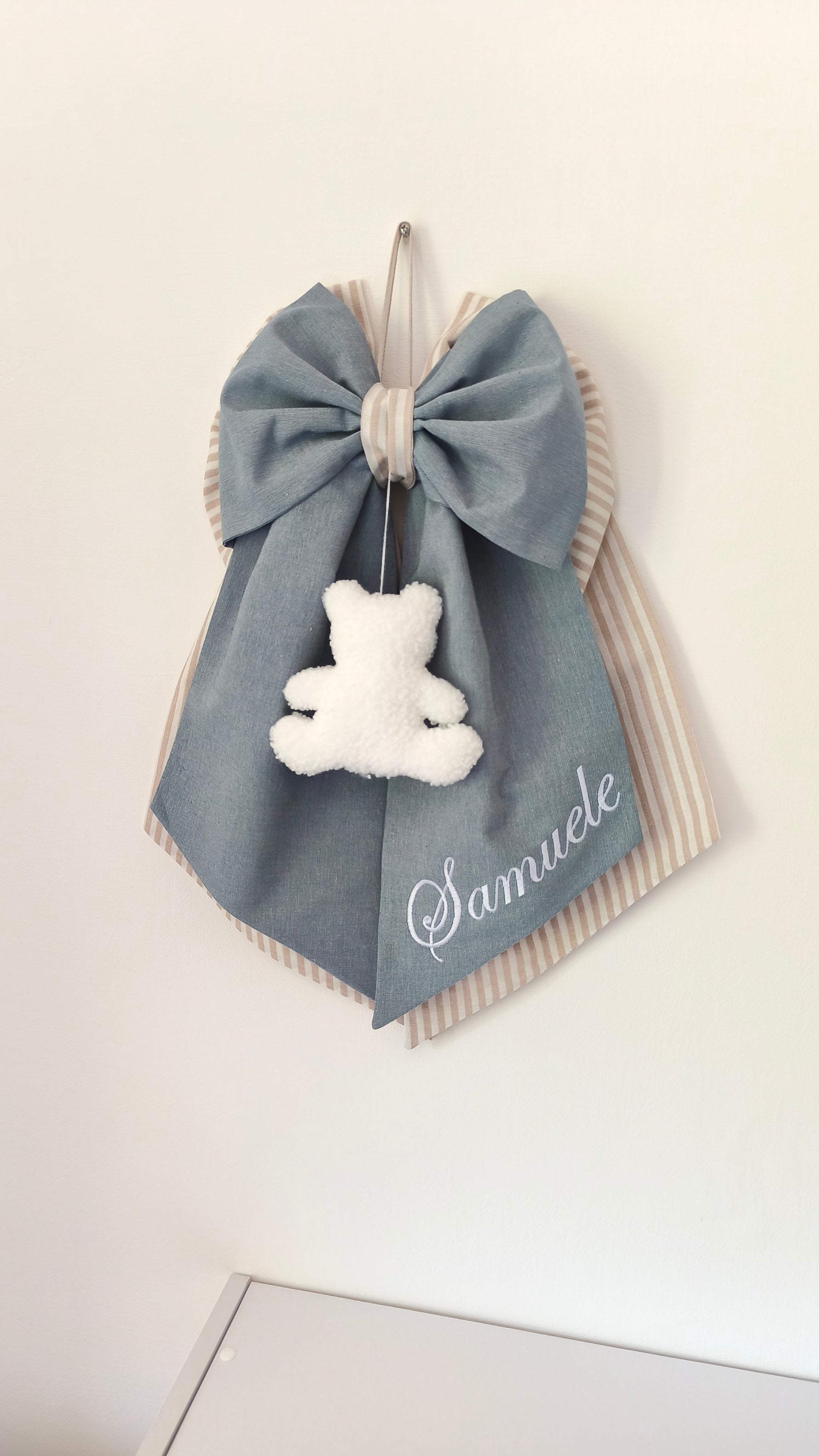 Coccarda nascita azzurro grigio con righe panna, orsetto peluche bianco e scritta nome ricamata