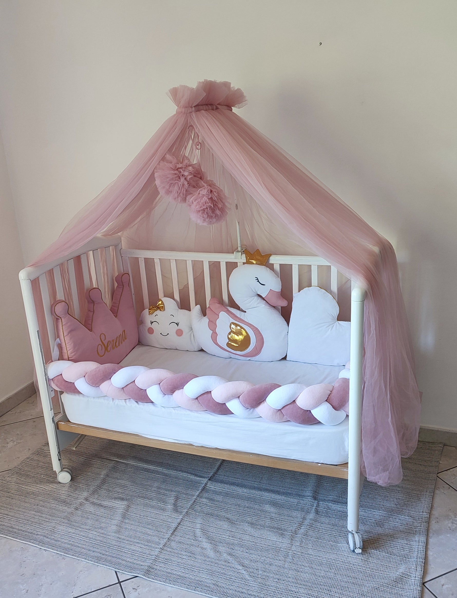 Culla bianca con velo a baldacchino rosa, paracolpi a treccia e cuscino a corona personalizzato