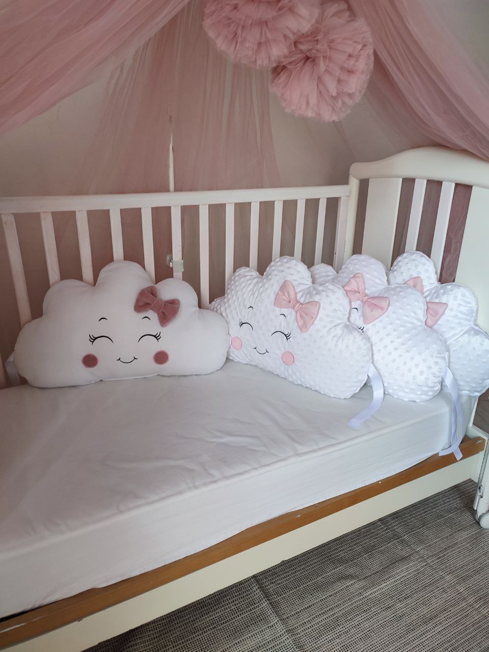 Cuscini decorativi a forma di nuvola bianchi e rosa antico con viso ricamato e fiocchetti per lettino neonata
