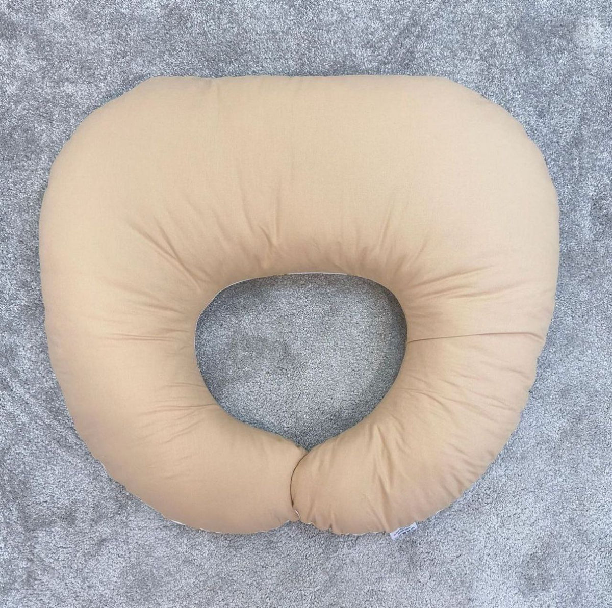 Lato posteriore beige tinta unita di un cuscino allattamento double face in cotone morbido per neonato.
