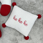 Dettaglio cuscino quadrato bianco ricamato ho ho ho con pon pon natalizi per letto e lettino