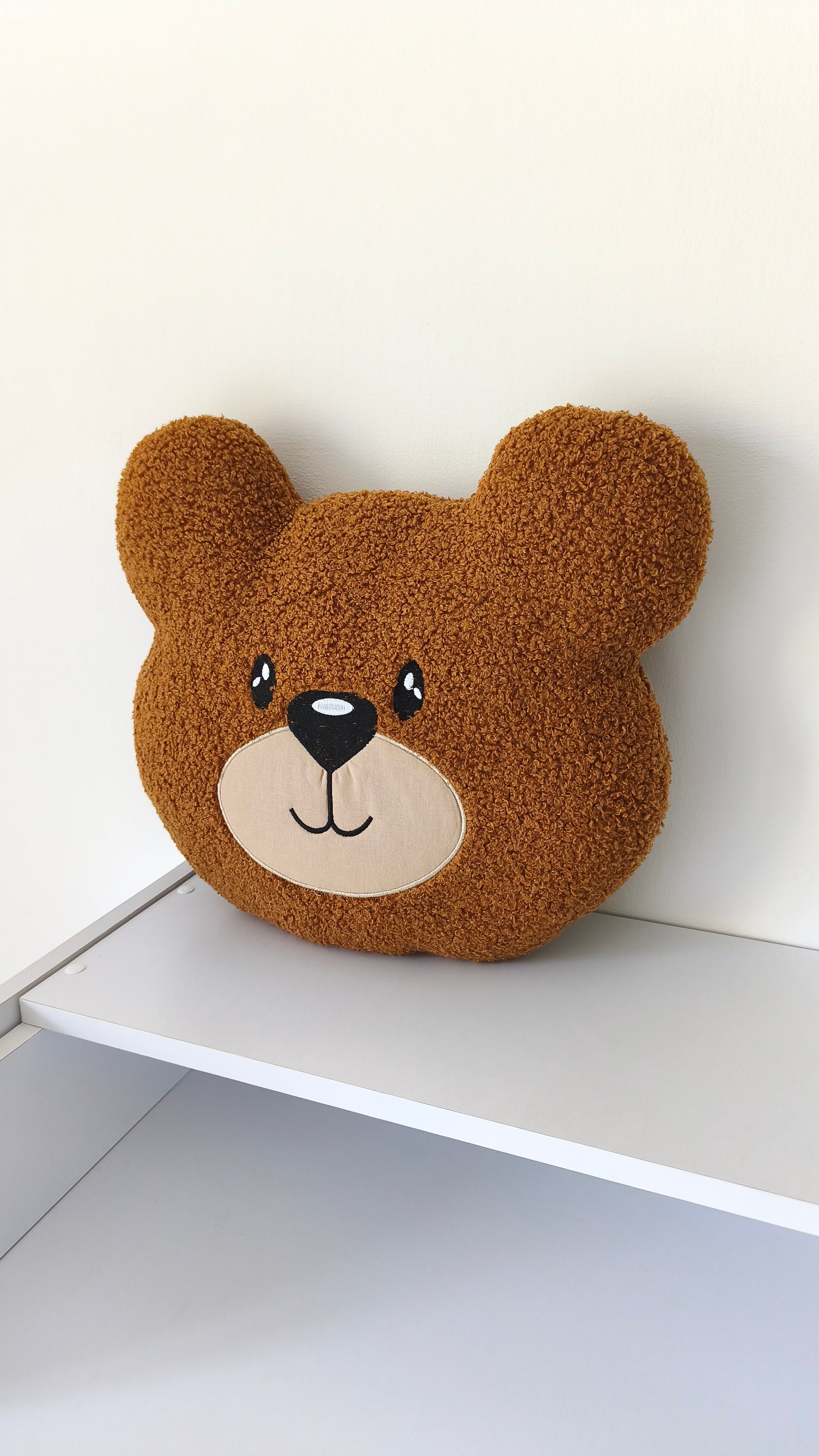 Cuscino paracolpi a forma di orsetto marrone in tessuto riccio bouclé, morbido accessorio d'arredo per lettino neonato.