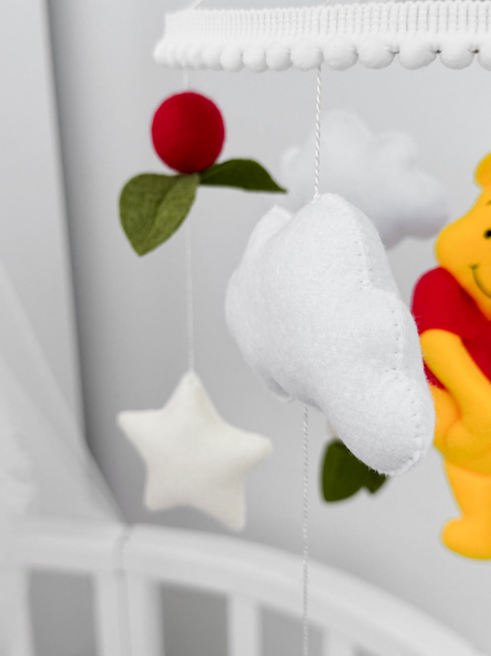 Giostrina musicale Winnie the Pooh e nuvole in feltro, dettaglio decorazioni fatte a mano per cameretta neonati.