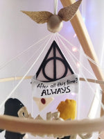 Dettaglio giostrina culla Harry Potter con boccino d'oro, simbolo doni della morte e scritta Always