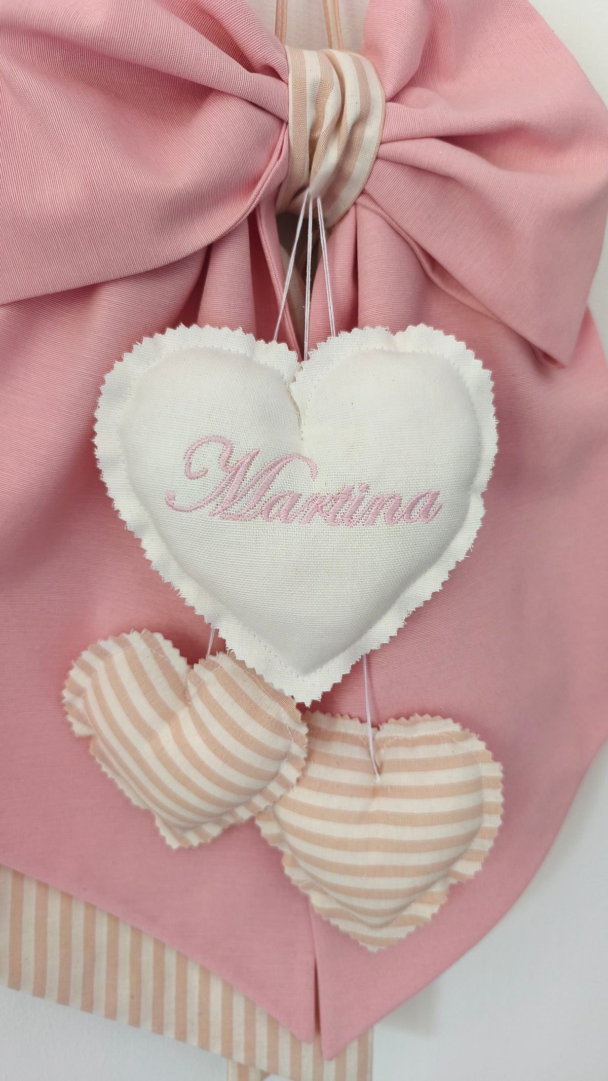 Dettaglio cuore ricamato con nome bambina su fiocco nascita rosa, cuoricini a righe beige