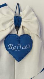 Dettaglio cuore blu ricamato con nome bambino su fiocco nascita panna