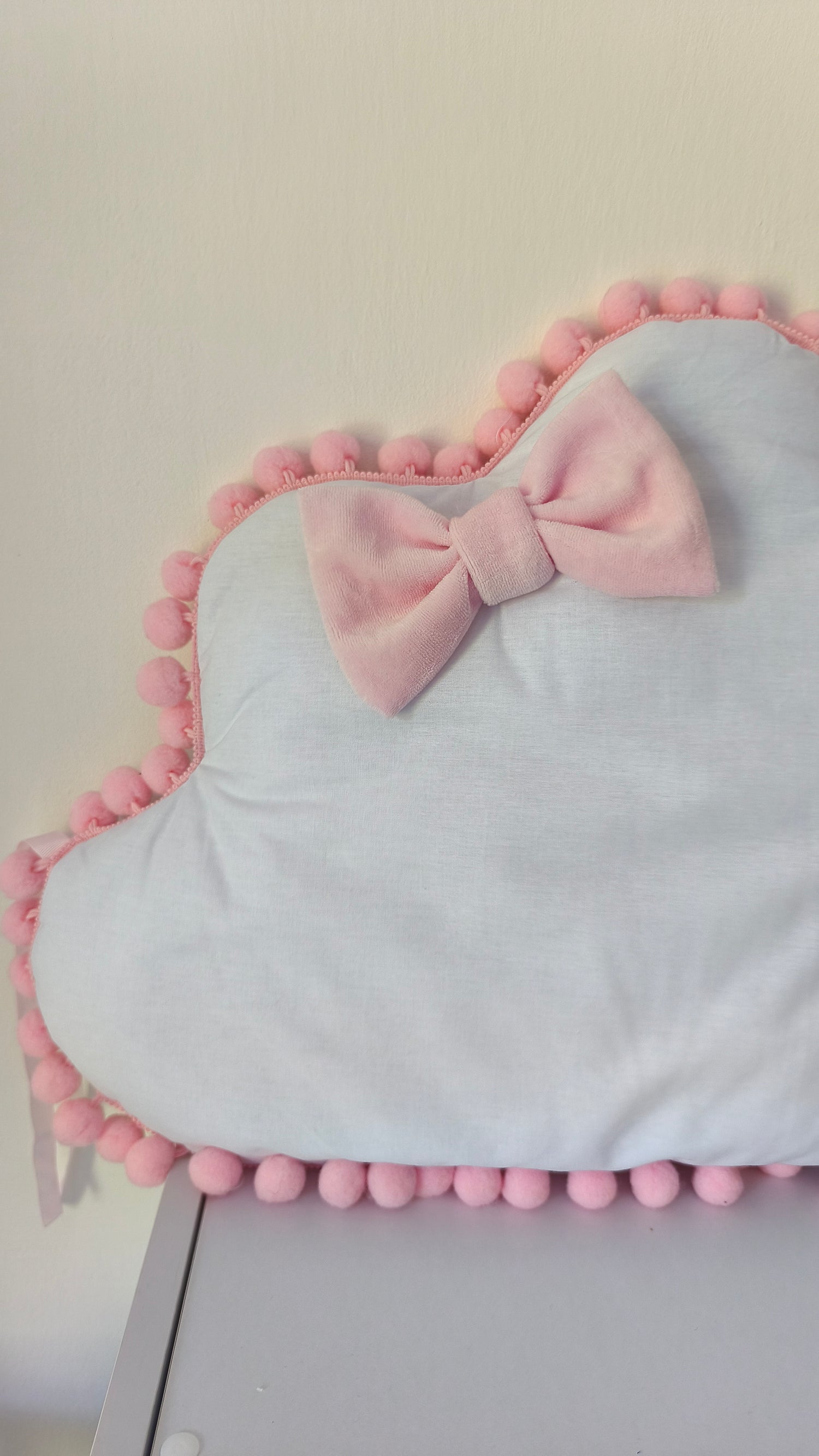 Dettaglio cuscino nuvola bianco con fiocco in velluto rosa e bordo pon pon, cameretta bambina