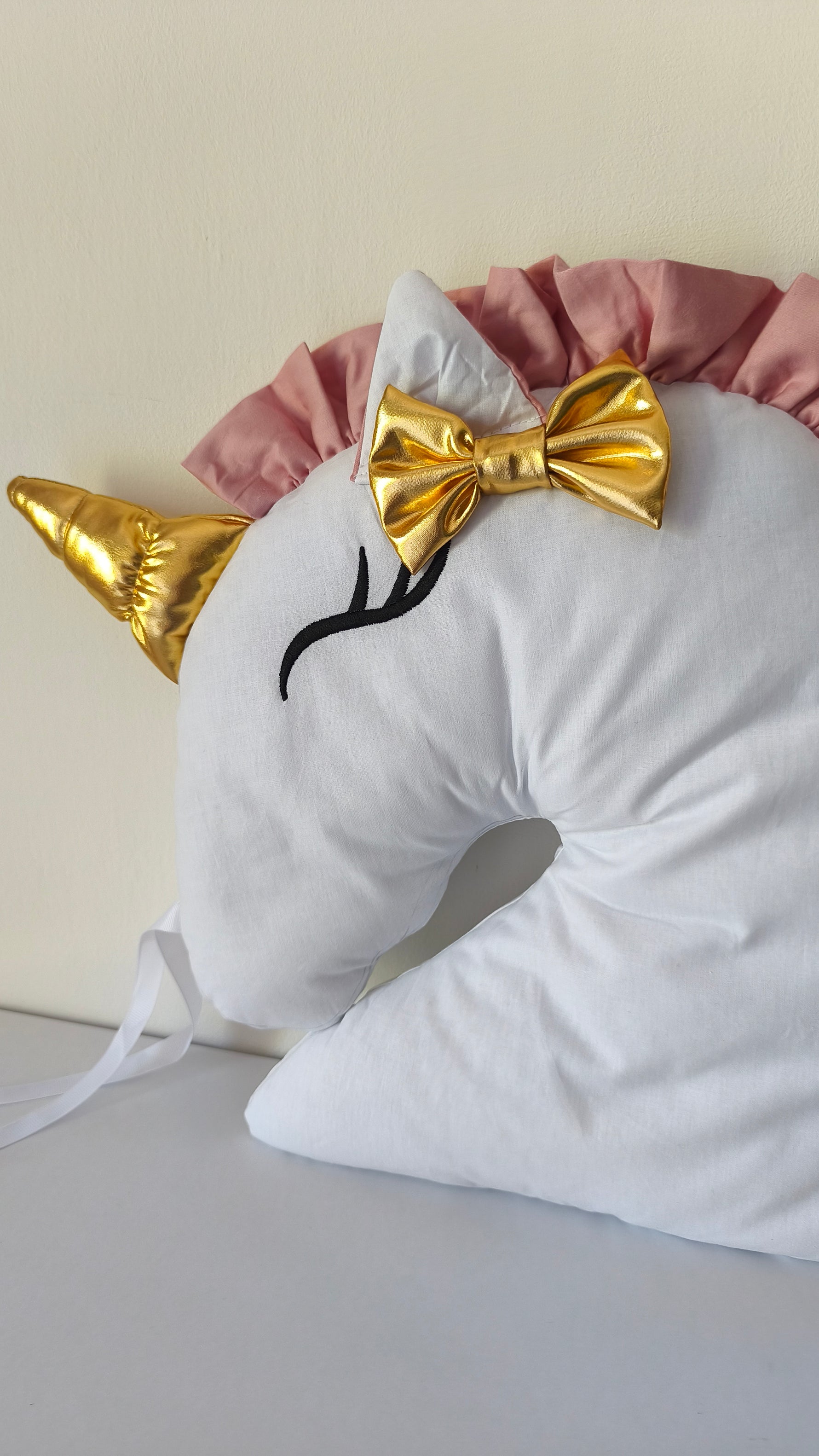Dettaglio cuscino unicorno bianco con corno dorato e fiocco oro, criniera rosa, cameretta bambina