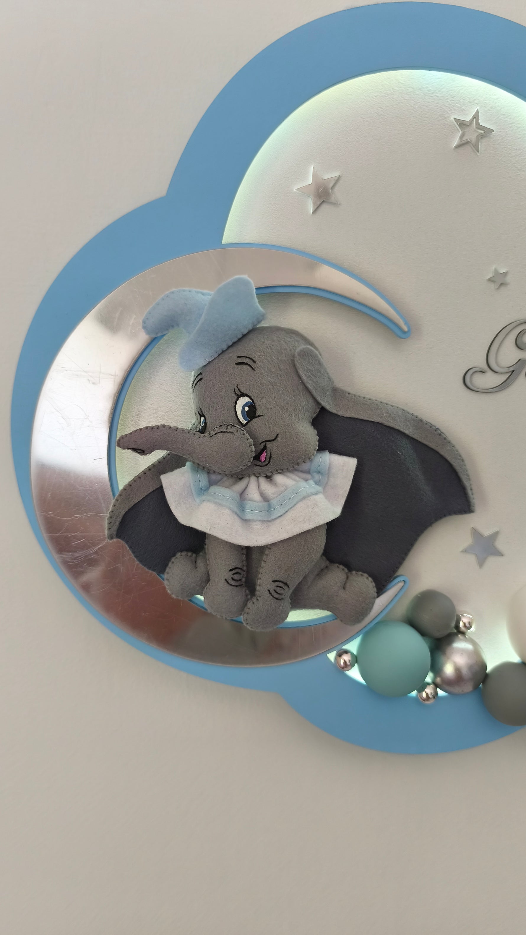 Dettaglio elefantino Dumbo in feltro su luna specchiata e sfere tiffany e grigie. Luce notturna personalizzata bimbo