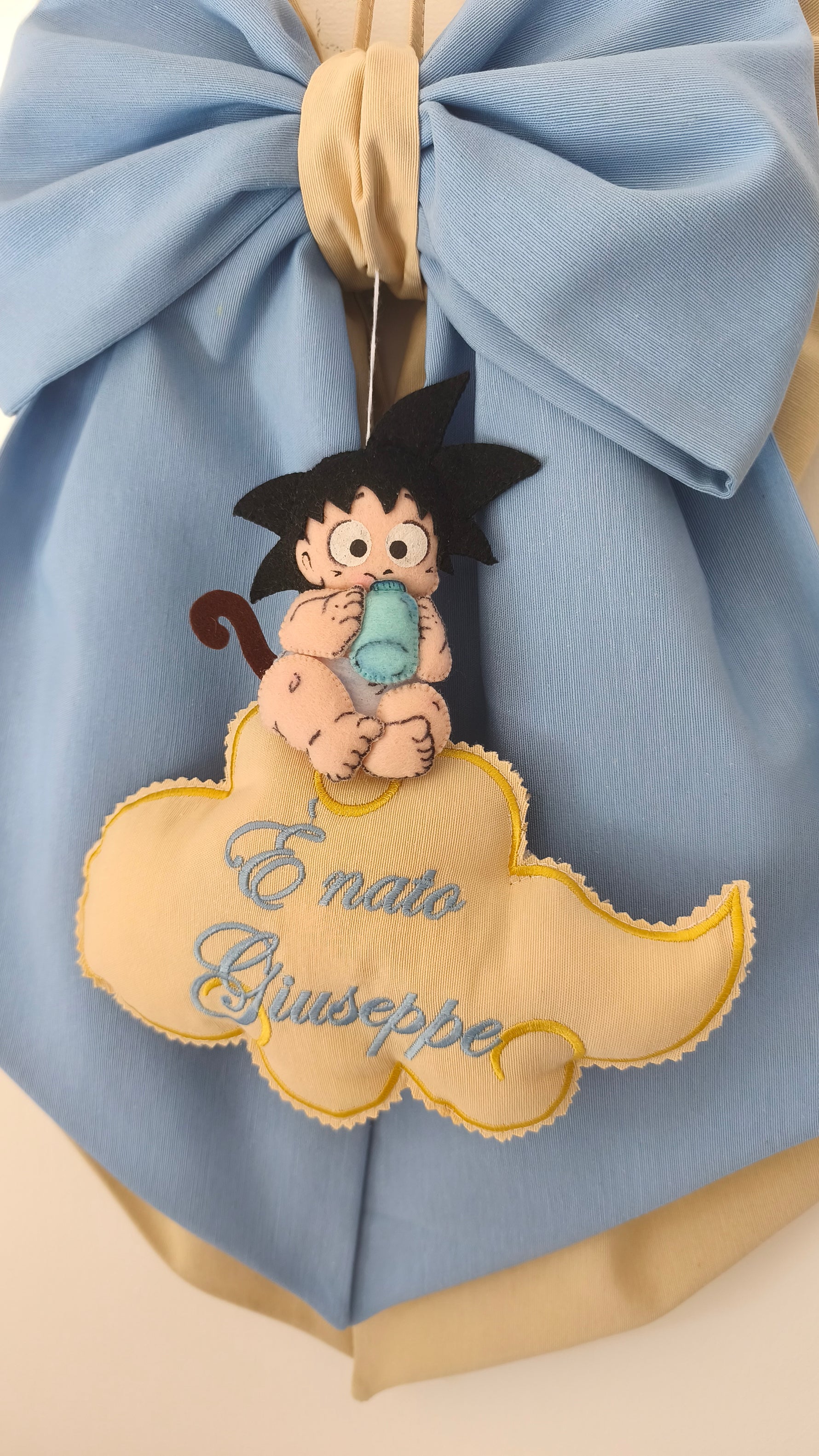 Dettaglio del ricamo fatto a mano su fiocco nascita con Goku baby e nuvoletta personalizzata