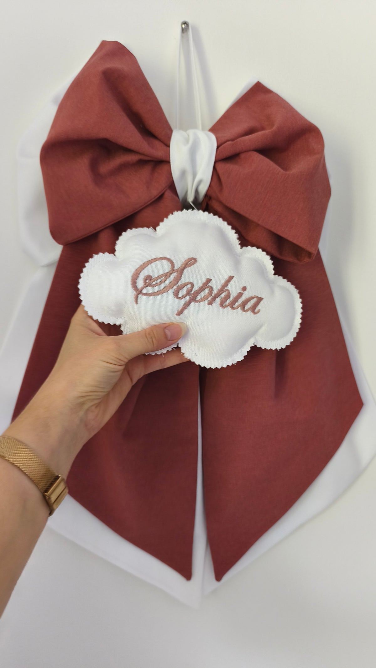 Dettaglio ravvicinato di una nuvoletta bianca ricamata a mano con il nome Sophia per fiocco nascita artigianale bicolore