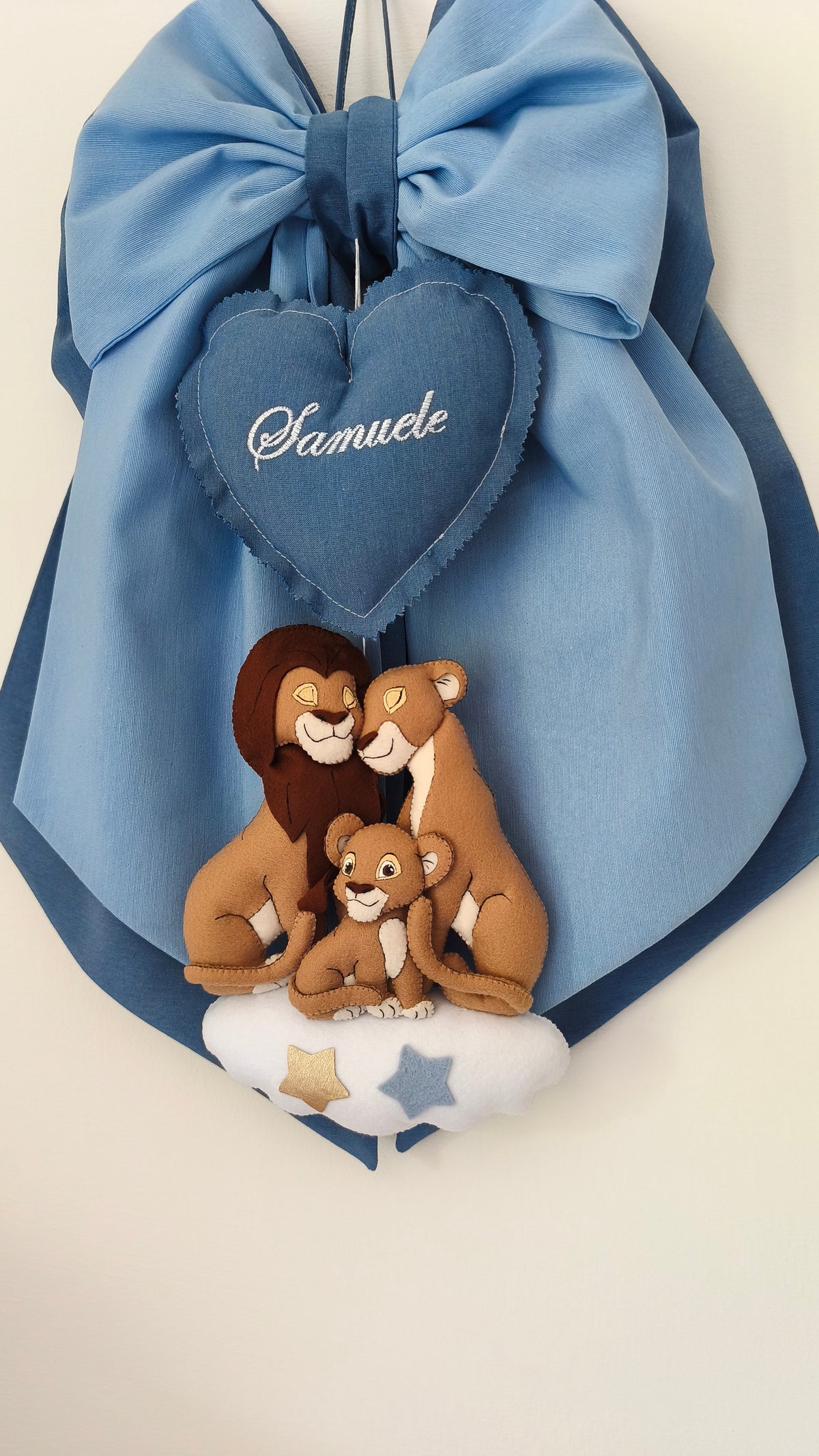 Dettaglio fiocco nascita azzurro con ricamo personalizzabile su cuore e personaggi Re Leone in feltro