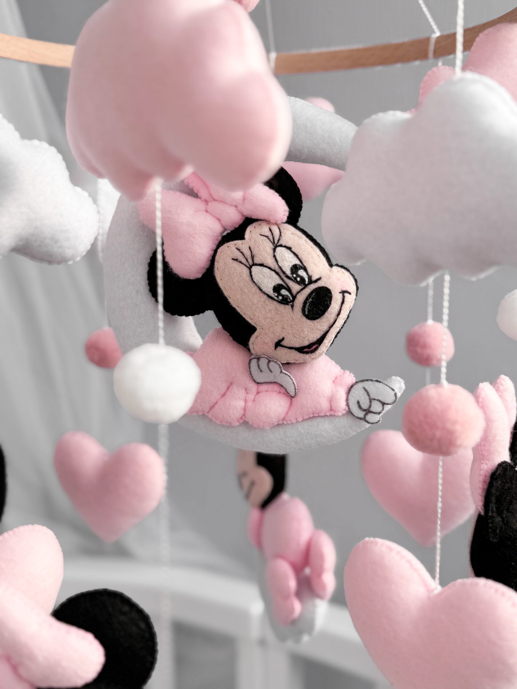 Dettaglio mobile culla Minnie Mouse feltro cucito a mano, nuvole bianche cuori rosa pon pon carillon neonata