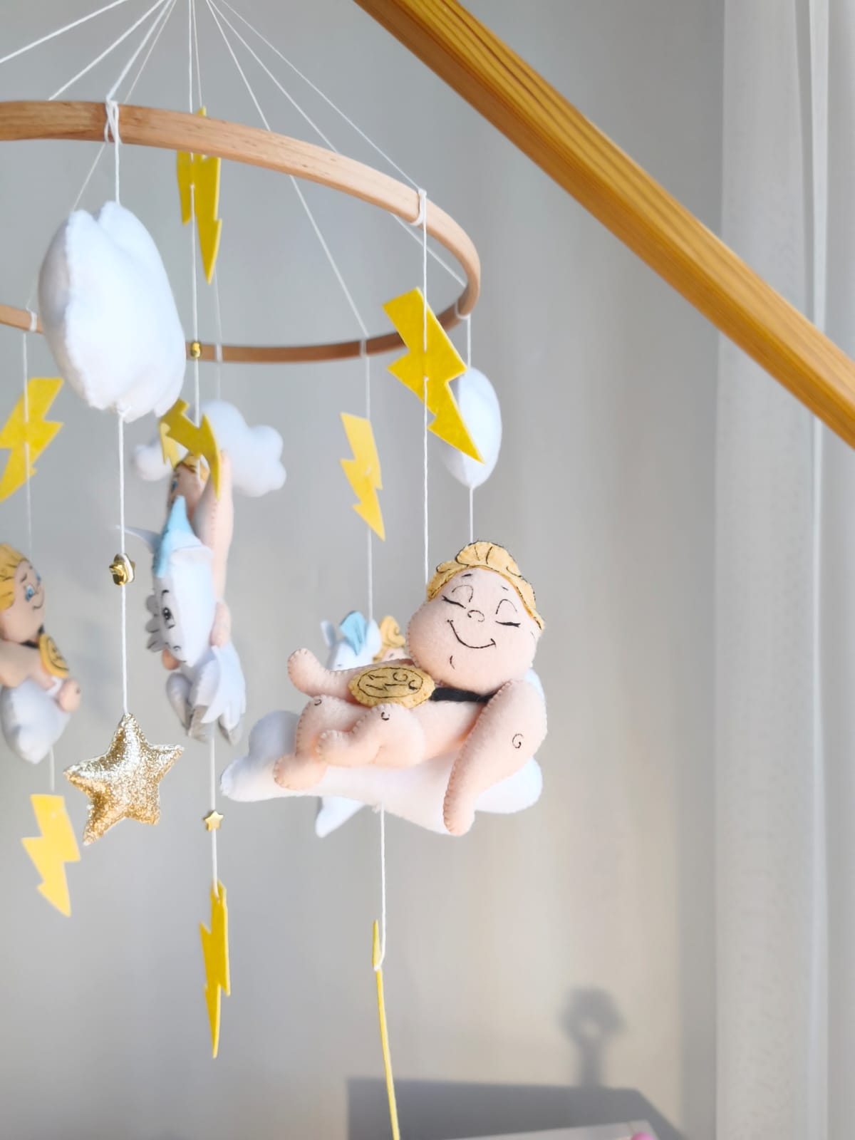 Dettaglio giostrina feltro con piccolo Hercules che dorme su una nuvola bianca con medaglia d'oro e fulmini.