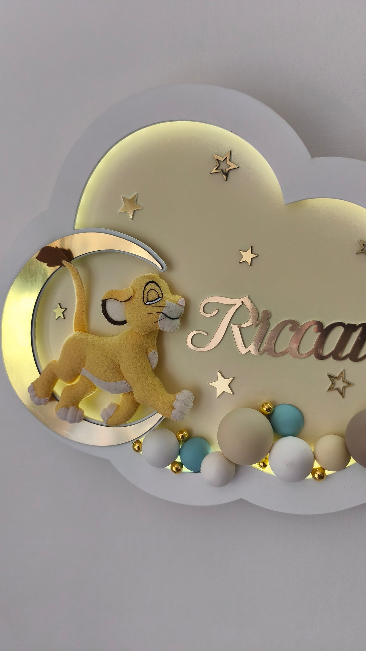 Dettaglio lampada nuvola beige con leoncino Simba in feltro sulla luna oro e nome per cameretta bimbo.