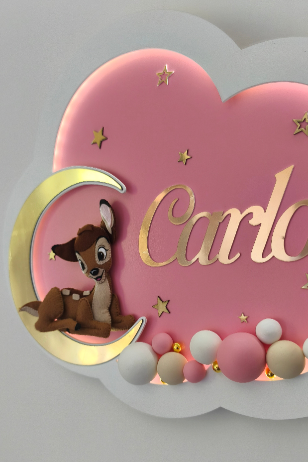 Dettaglio luce notturna nuvola con Bambi su luna oro e primo piano di palline in legno dipinte rosa e panna per bimba