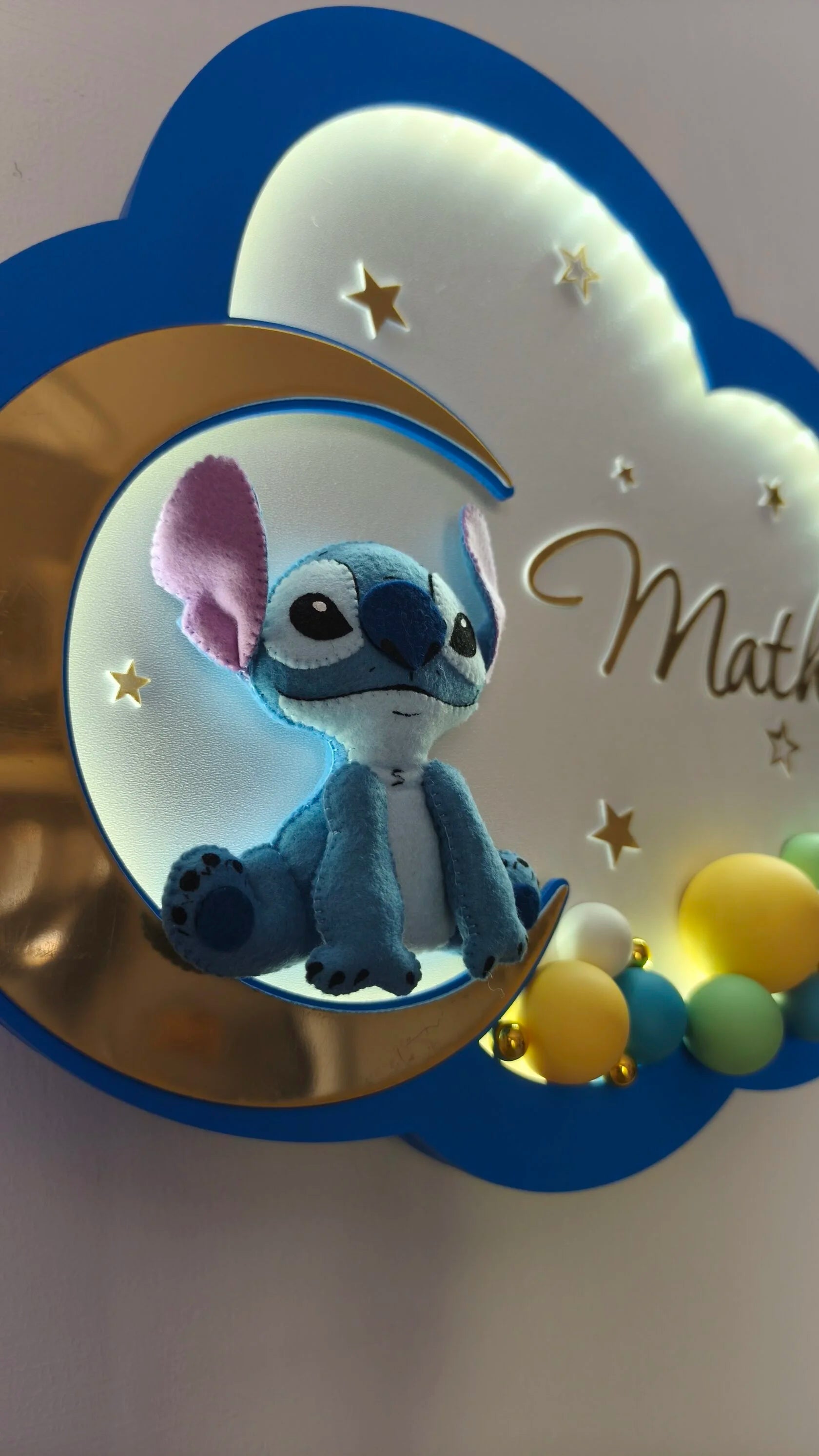 Dettaglio luce notturna nuvola Stitch in feltro cucito a mano sulla luna dorata, bordo blu royal, stelle dorate