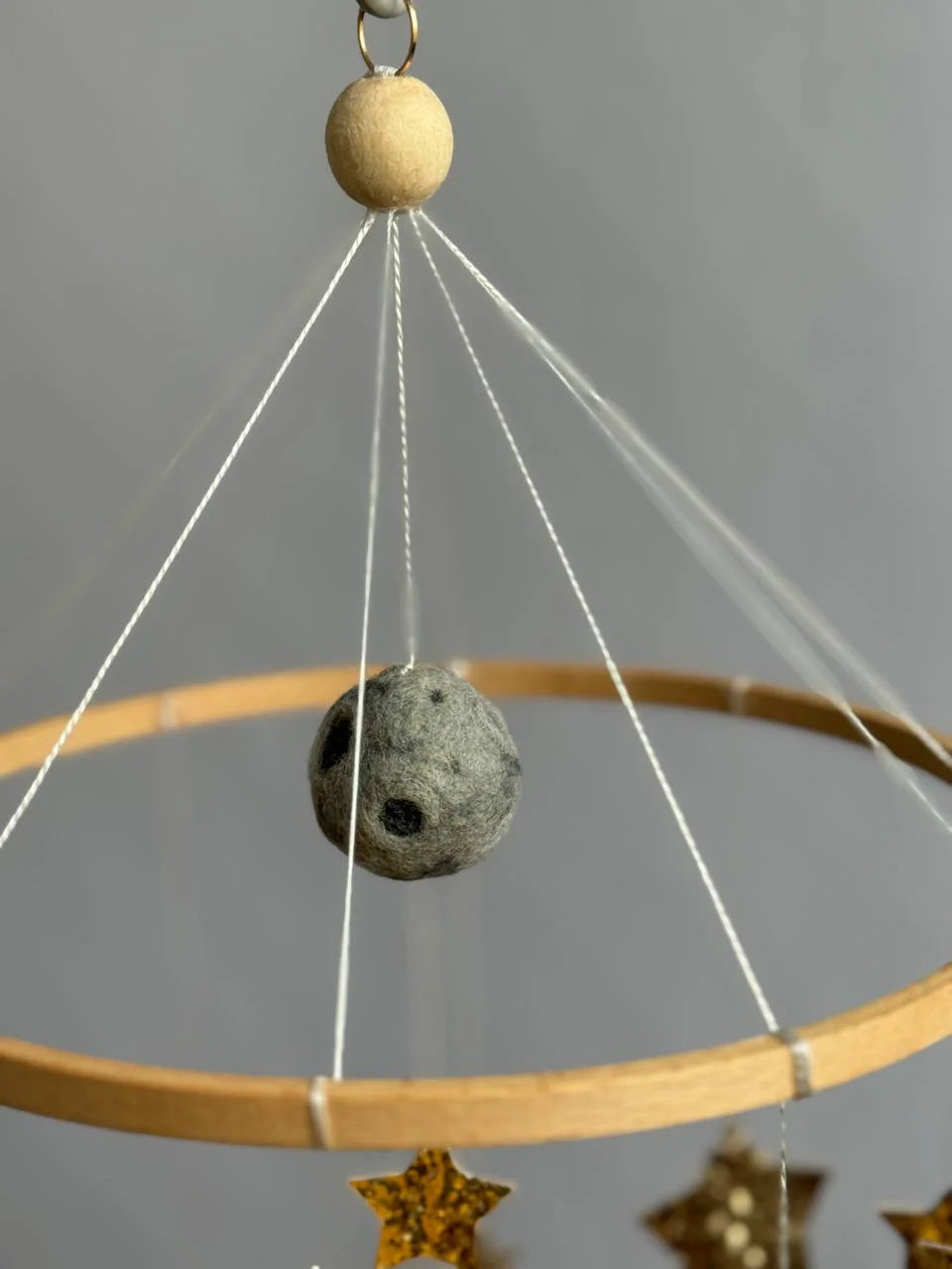 Luna in feltro grigio con crateri appesa su cerchio legno, dettaglio mobile culla spazio artigianale neonato