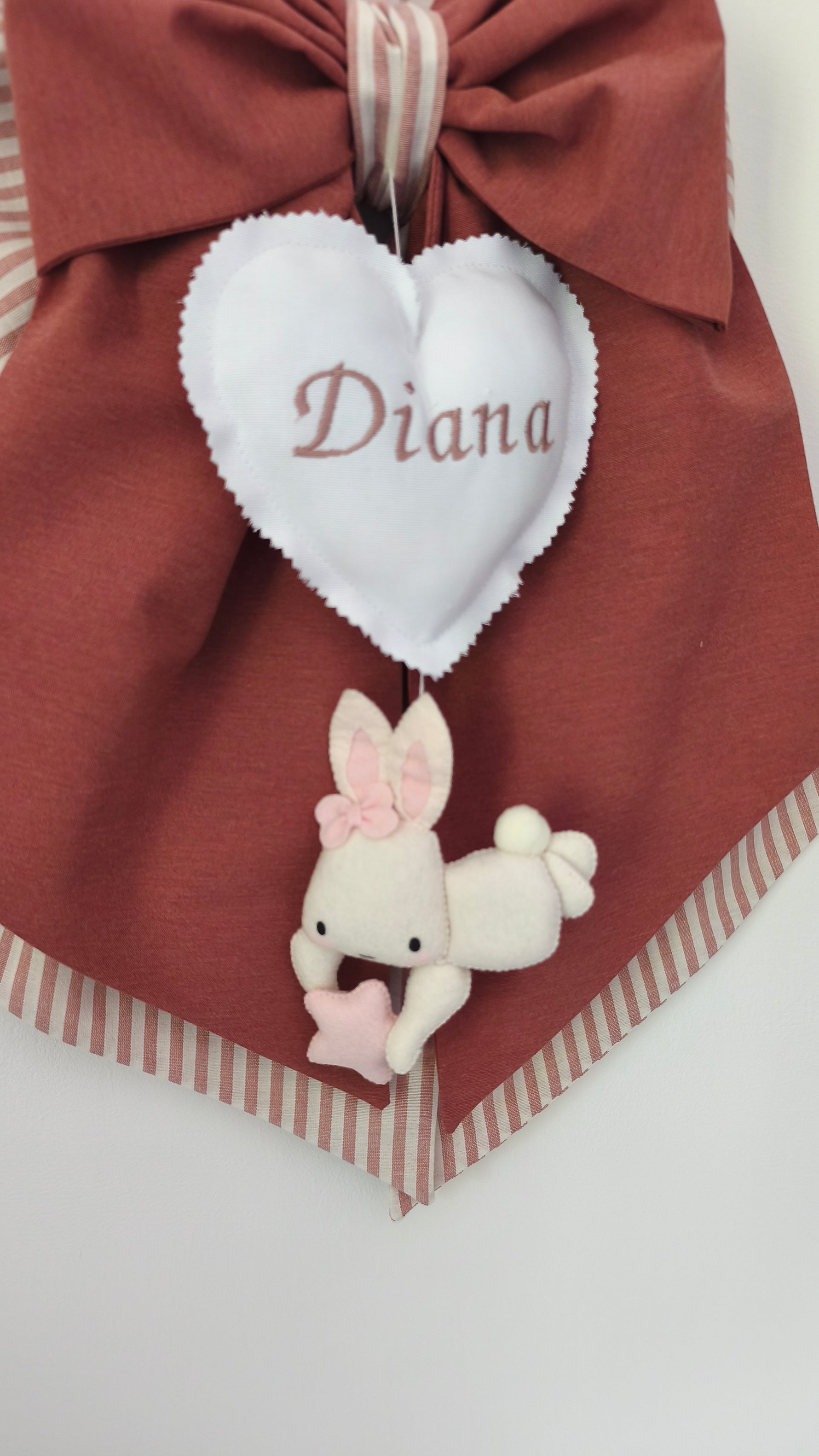 Primo piano del cuore bianco ricamato a mano su fiocco nascita bimba a tema coniglio
