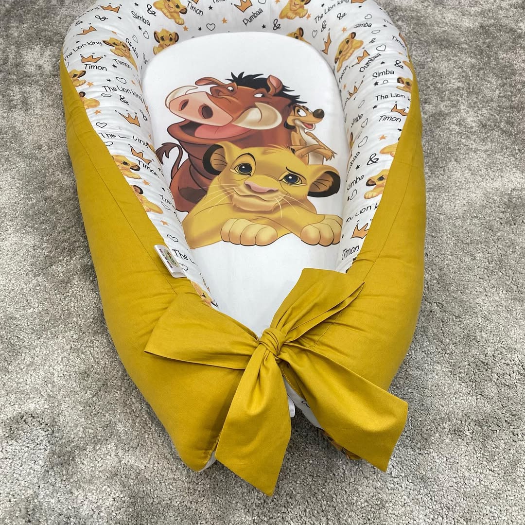 Riduttore lettino giallo senape con fiocco, culla nido neonati bianco con scritte e corone Disney.