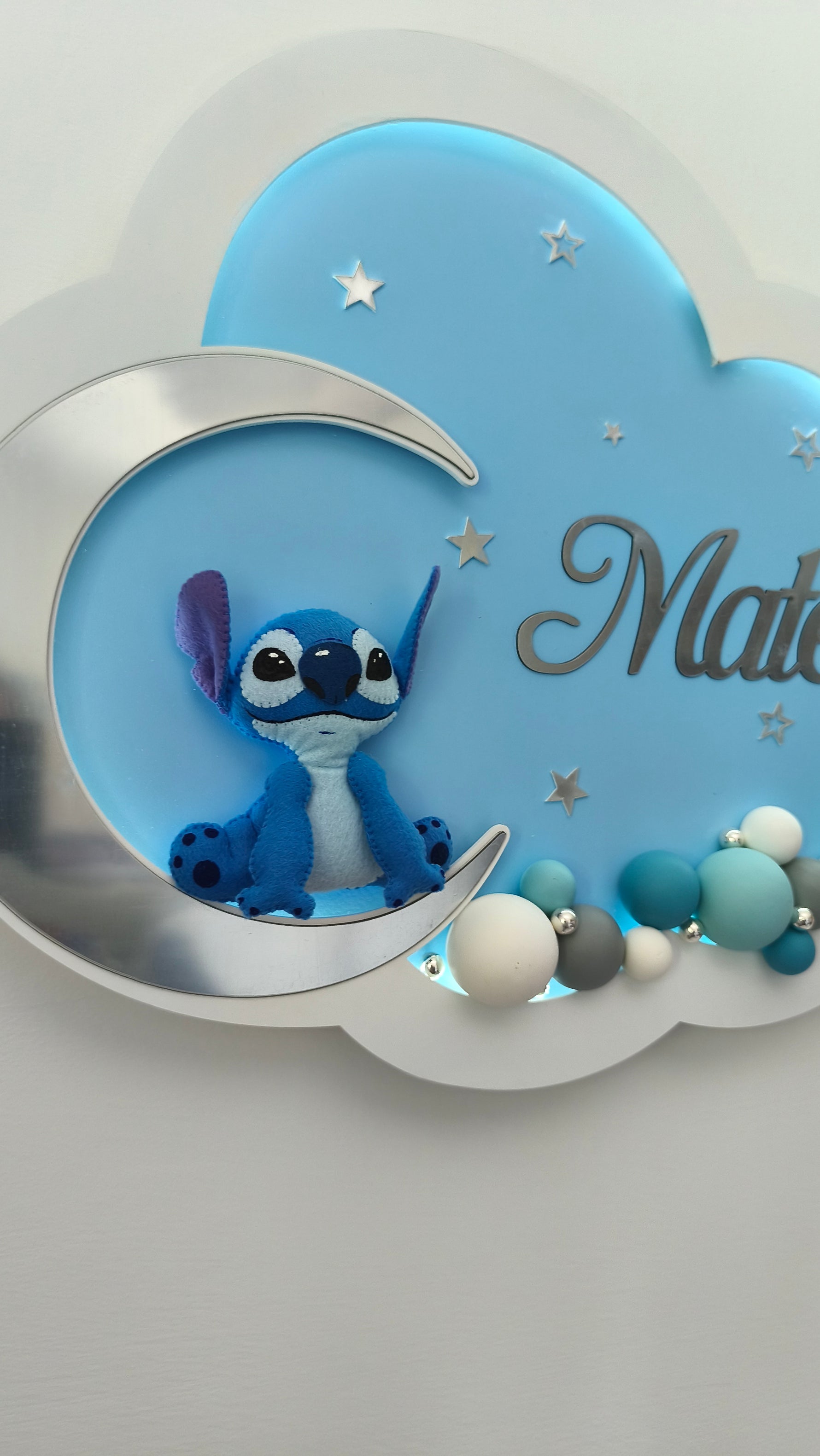Dettaglio di Stitch in feltro sulla luna d'argento, particolare di una lampada nuvola personalizzata con nome