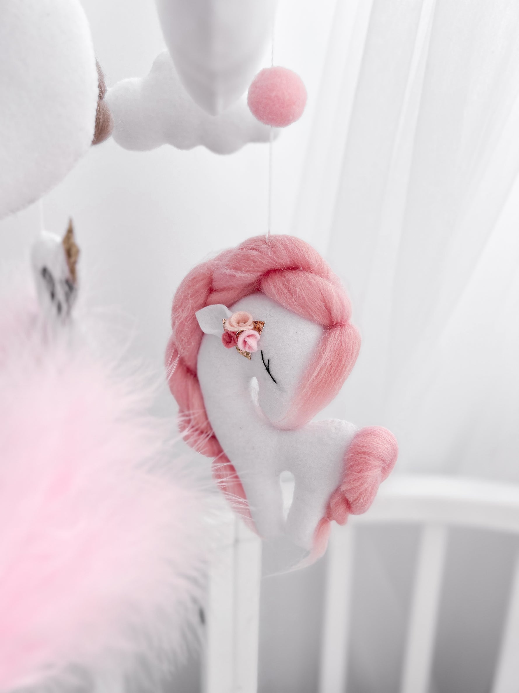 Dettaglio giostrina feltro unicorno bianco criniera rosa intrecciata fiorellino oro nuvole pompon culla