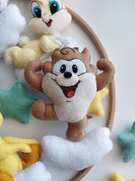Dettaglio di Taz Baby Looney Tunes in feltro marrone su nuvola bianca con stelle colorate, particolare di una giostrina per culla