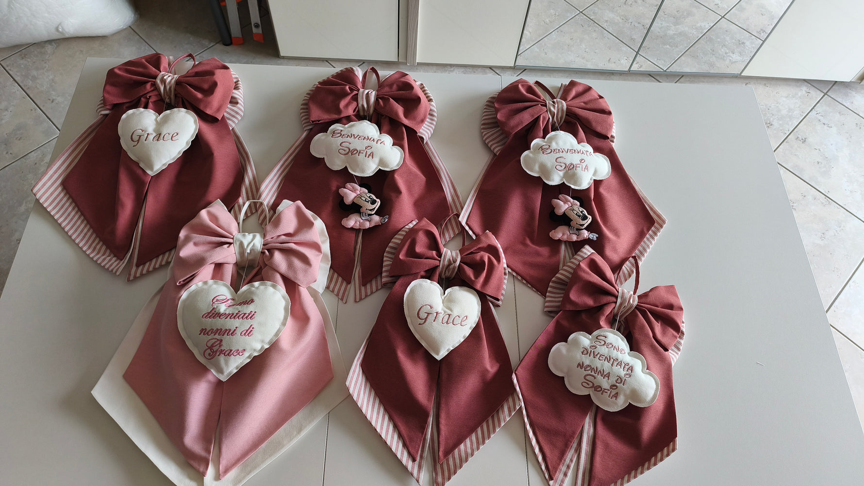 Collezione fiocchi nascita rosa antico con nomi ricamati, nuvolette Minnie e dediche speciali per i nonni, fatti a mano.