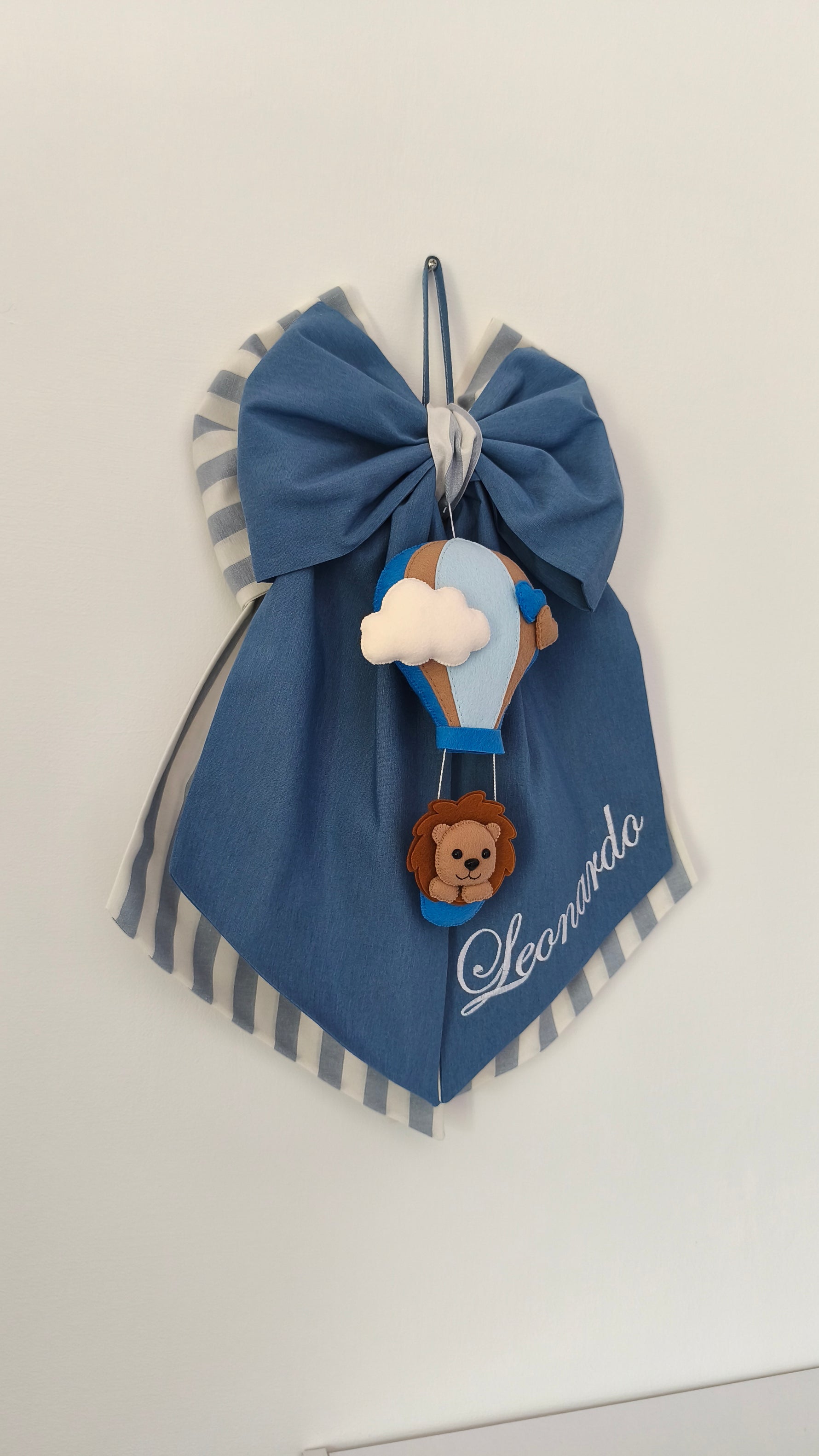 Fiocco nascita artigianale blu a righe con mongolfiera e leoncino, decorazione cameretta personalizzabile con nome.