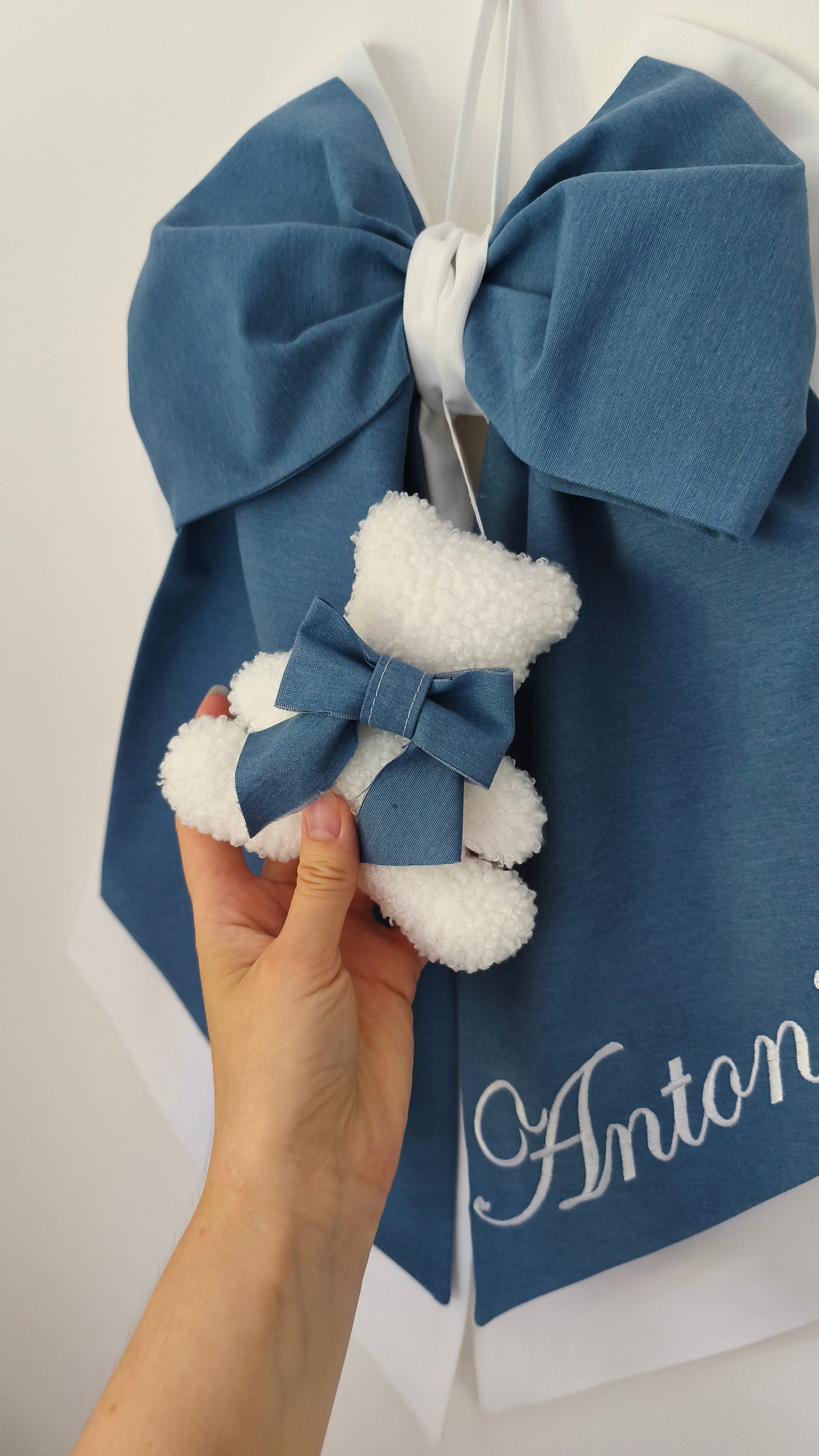 Orsetto bouclé bianco su fiocco nascita azzurro personalizzato con nome ricamato, dettaglio cucito a mano