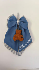 Coccarda nascita blu con righe grigie e bianche, orsetto bouclè color ruggine e scritta nome bianca