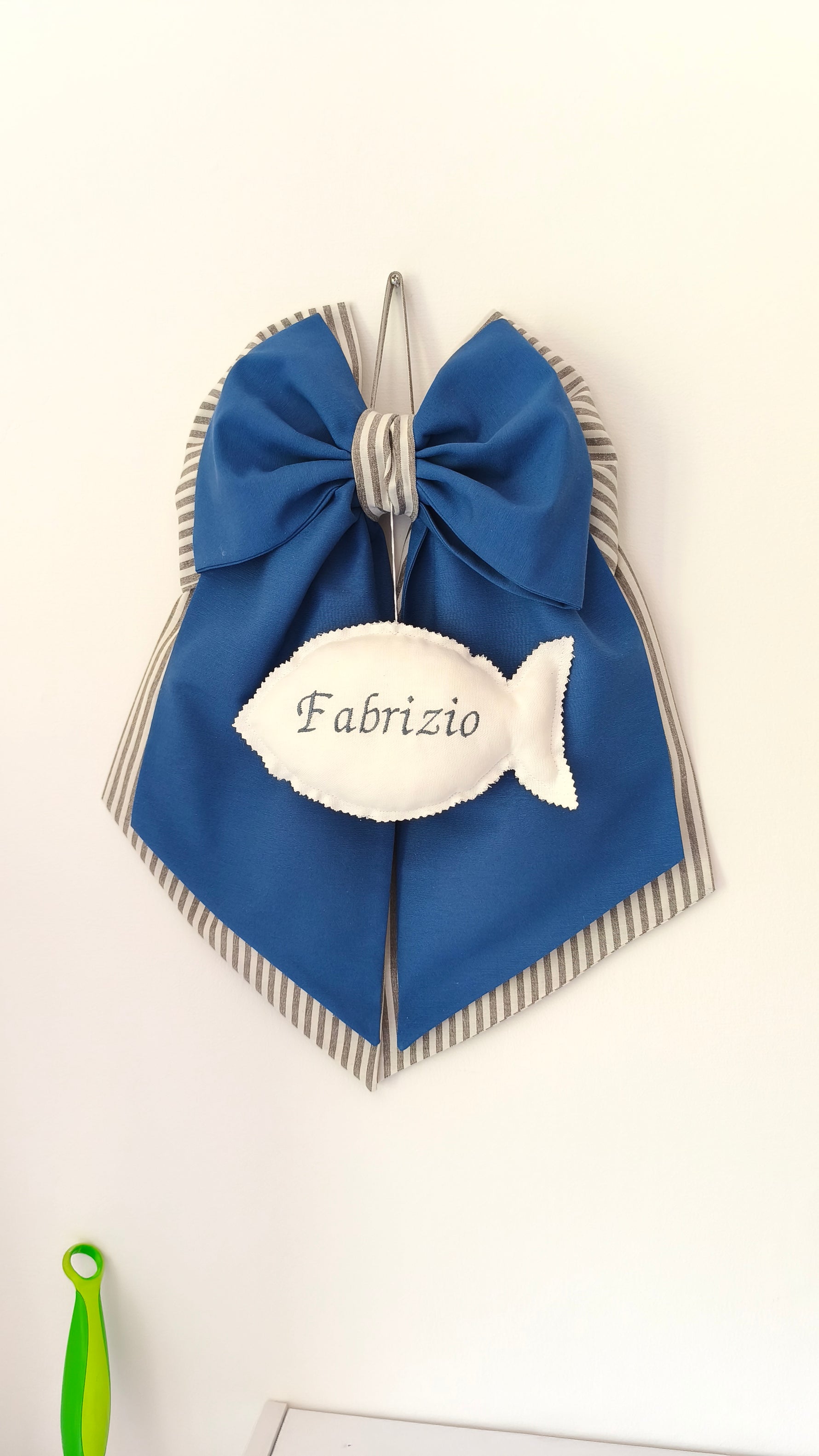 Fiocco nascita azzurro e blu personalizzato con nome ricamato su un inserto a forma di pesciolino bianco per nascita bimbo.