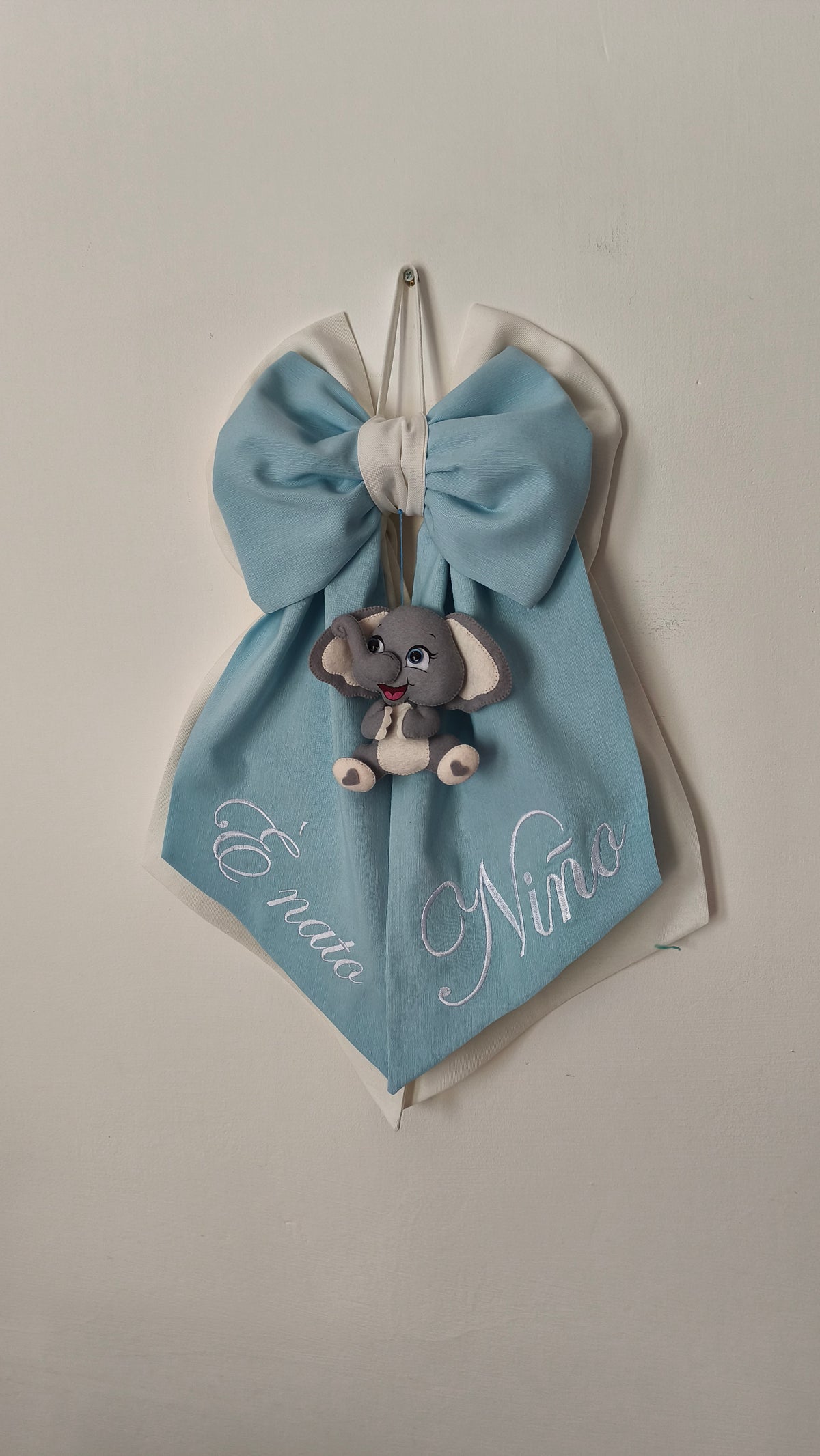 Fiocco nascita azzurro con scritta laterale personalizzata "È nato Nino" ed elefantino in pannolenci – decorazione porta ospedale bambino