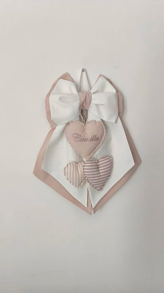 Fiocco nascita panna e rosa antico personalizzato con nome ricamato su cuore e ciondoli pendenti a righe.