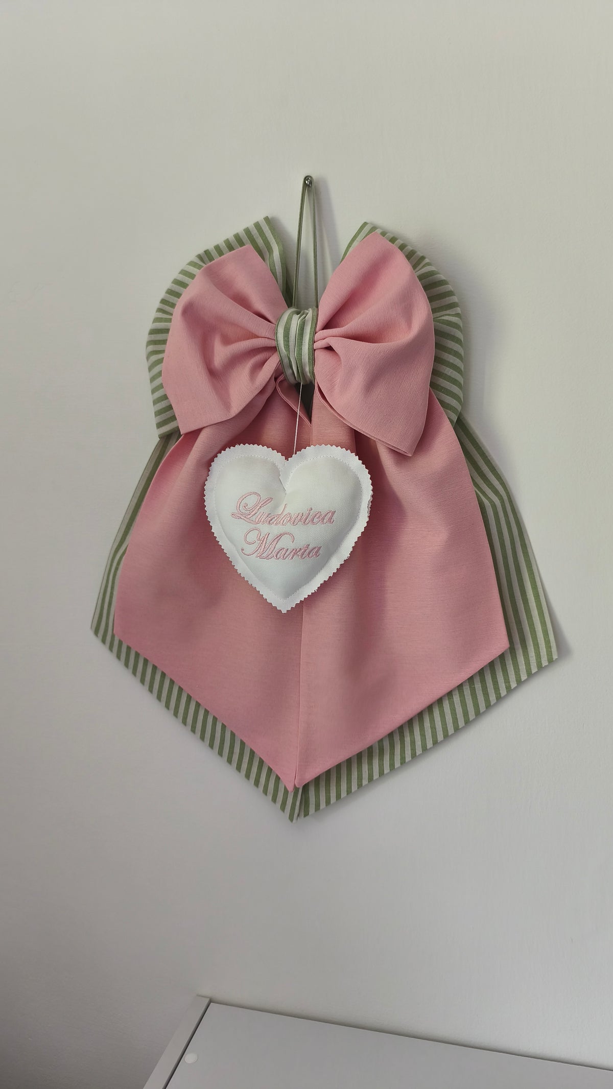 Fiocco nascita artigianale in tessuto rosa baby e verde salvia a righe con grande cuore bianco imbottito e doppio nome ricamato.