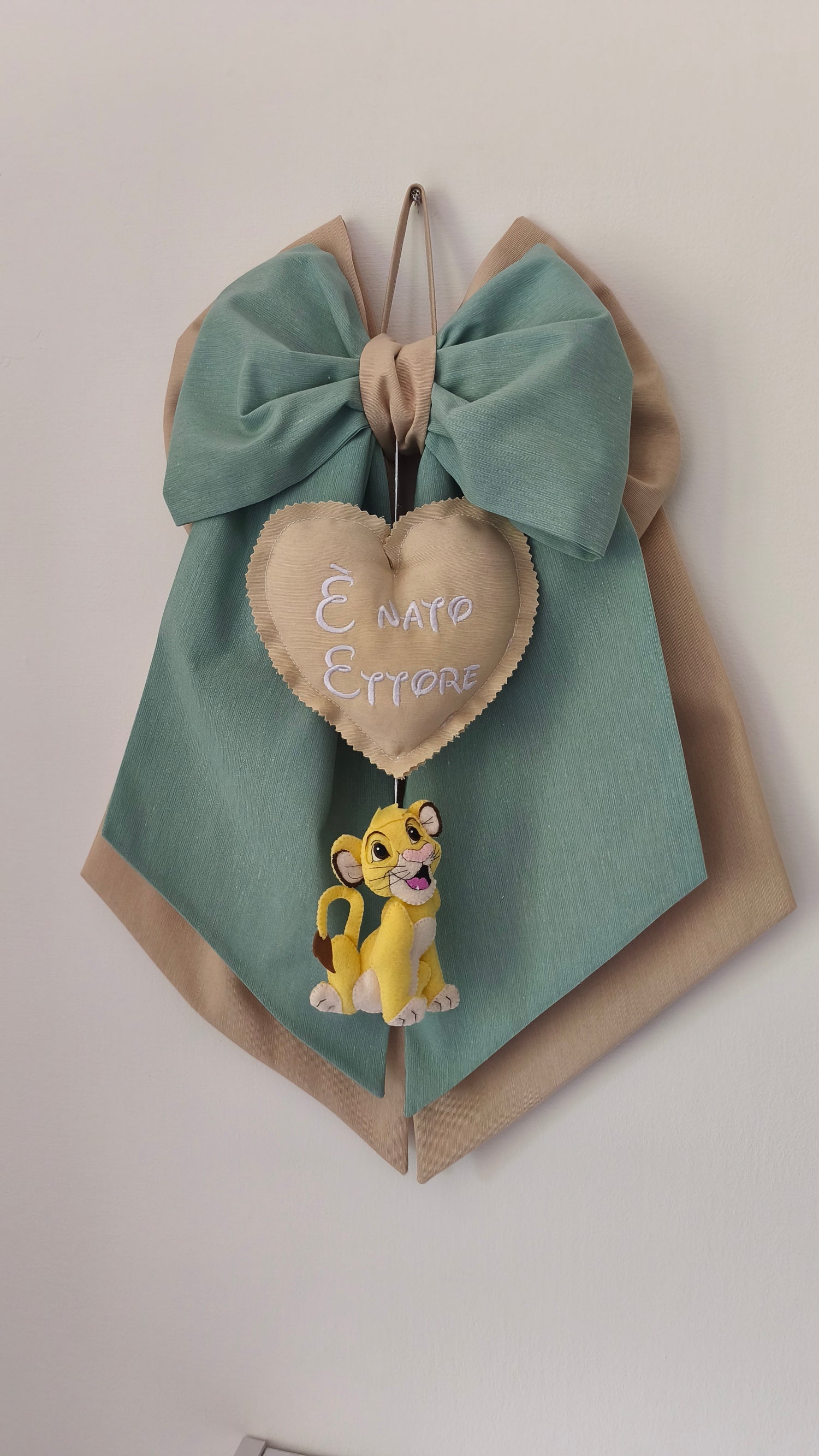Fiocco nascita personalizzabile verde salvia e beige con cuore ricamato "È nato" e cucciolo di Simba in feltro.