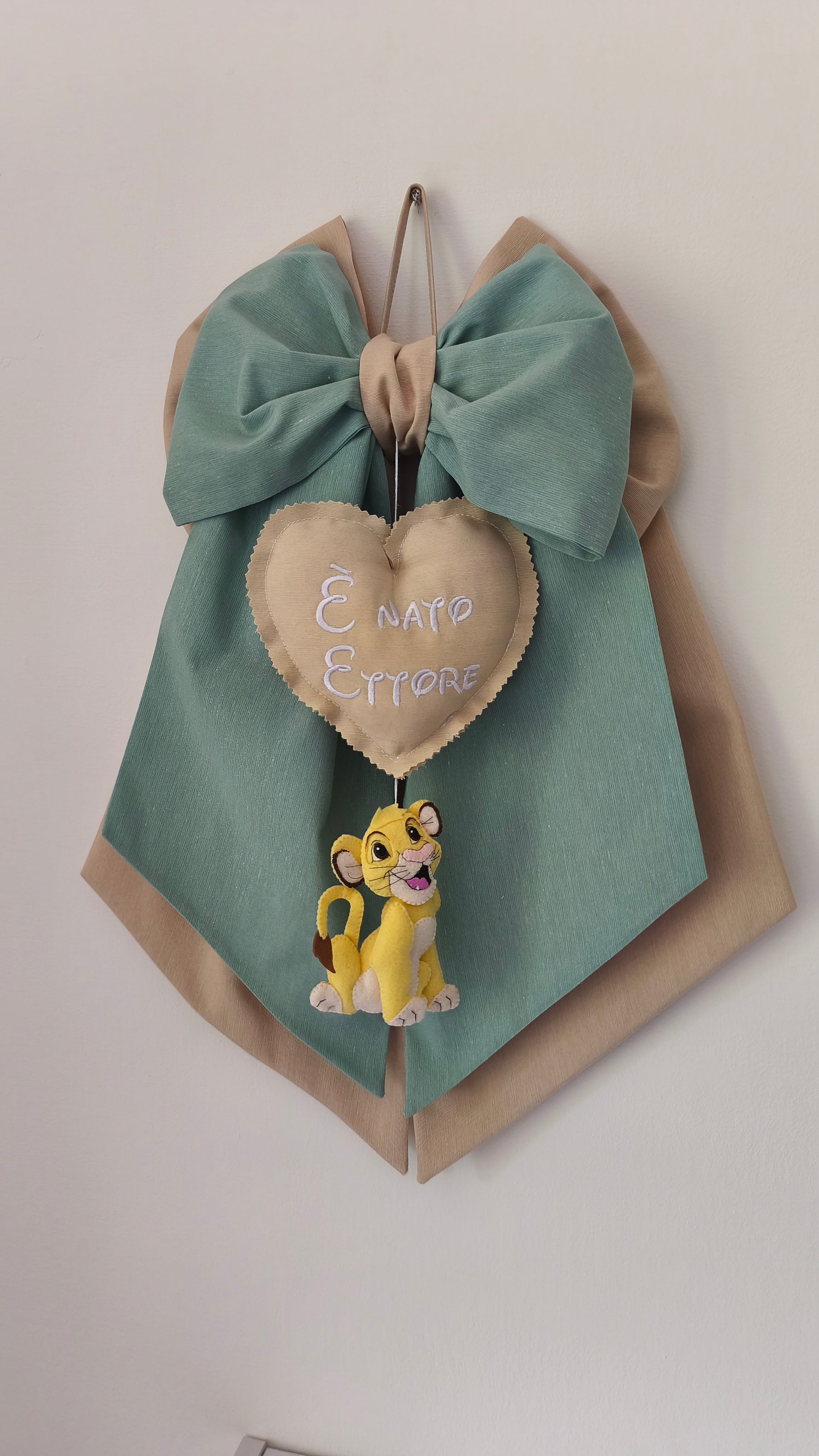 Fiocco nascita personalizzabile verde salvia e beige con cuore ricamato "È nato" e cucciolo di Simba in feltro.