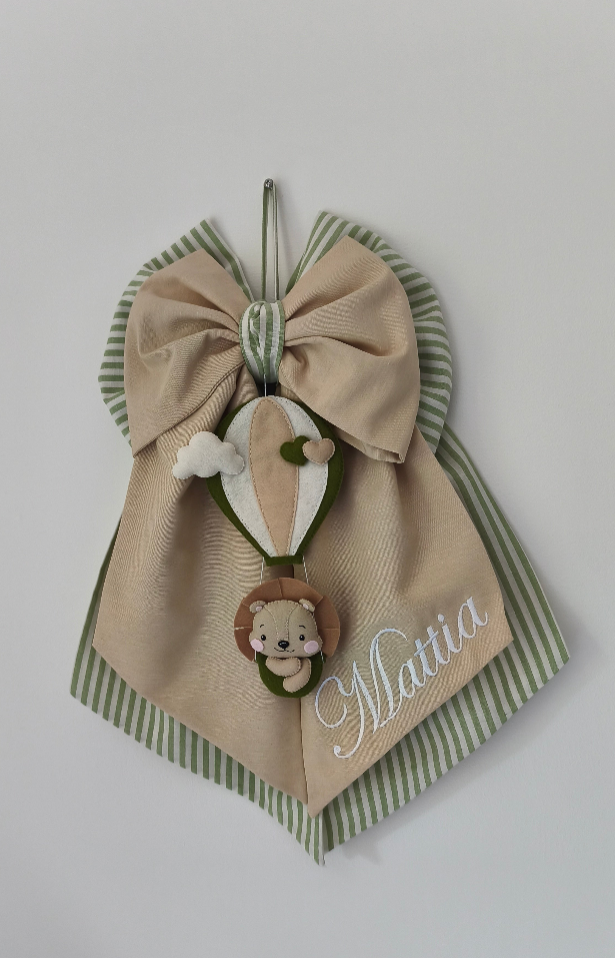 Fiocco nascita beige e verde salvia a righe con mongolfiera pendente, piccolo leone in tessuto e coda personalizzabile.