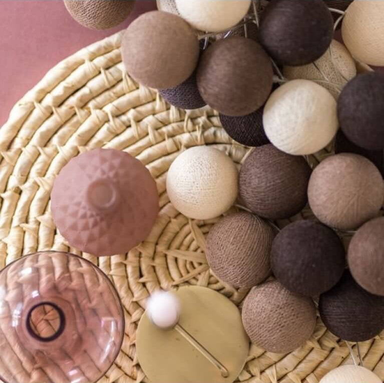 Palline di cotone ghirlanda tonalità marrone e beige su tavolo intrecciato, primo piano