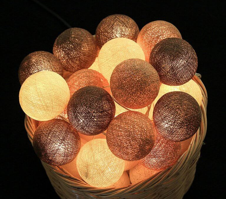Palline luminose LED cotone marroni e beige accese in cesto vimini, effetto atmosfera