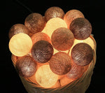 Palline luminose LED cotone marroni e beige accese in cesto vimini, effetto atmosfera